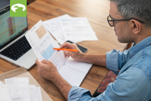 Man looking at papers and laptop